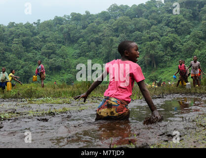 Congolese villagers fill their water supply from this Muddy pond. The only good water source they have. Stock Photo