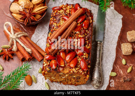 Homemade holiday Fruitcake with nuts, fruits and spices. Almonds, cinnamon, star anise, cardamom on the table. Traditional English pastries. Christmas Stock Photo