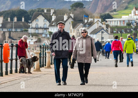 Sidmouth, Devon, UK.  13th March 2018.  UK Weather.  Visitors and residents enjoying a walk along the seafront at the seaside town of Sidmouth in Devon on a warm sunny spring afternoon.  Picture Credit: Graham Hunt/Alamy Live News. Stock Photo