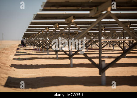 Aswan, southern Egypt, 13 March 2018. People seek shelter from the sun while standing under solar panels during the inauguration ceremony for the first stage of the Infinity 50 Solar Park near Aswan, southern Egypt, 13 March 2018. Once completed the solar power plant is supposed to be the biggest in the world with an output of 1.86 gigawatts. Photo: Oliver Weiken/dpa Credit: dpa picture alliance/Alamy Live News Stock Photo