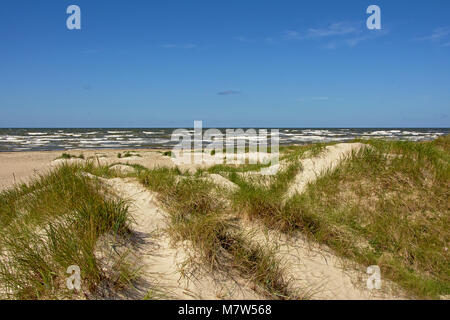 Dunes with grass along the Baltic sea beach of Liepaja on a sunny day with clear blue sky Stock Photo