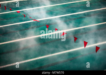 Corridor Lanes and flags in swimming pool with clean blue water. Fog over the water. Sport Competition. Stock Photo