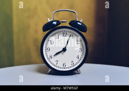 Retro alarm clock on table with vintage color background Stock Photo