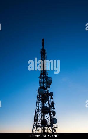 silhouette of antenna transmission telecommunication tower against blue morning sky before sunrise Stock Photo