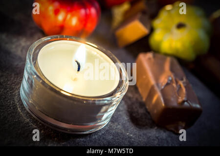 Halloween Decoration With One Candle, Chocolate And Pumpkins On Slate Stock Photo