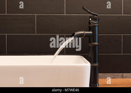Modern white square sink in bathroom with black tiles and black faucet in shape of bamboo. Modern bathroom design Stock Photo