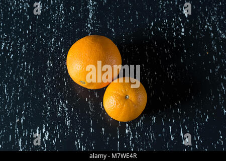 Two whole oranges on black wooden kitchen table. Stock Photo