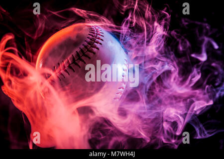 White baseball ball in multi-colored red smoke from a vape on a black isolated background Stock Photo