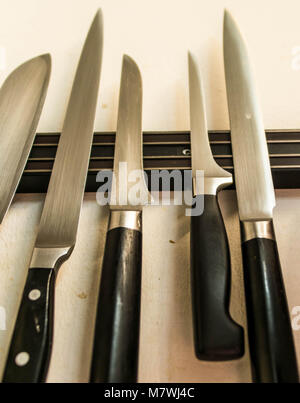 A set of high quality kitchen cook knives tools on a magnet board hanging on the wall Stock Photo