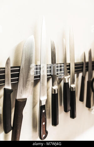 A set of high quality kitchen cook knives tools on a magnet board hanging on the wall Stock Photo