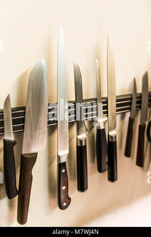 A set of high quality kitchen cook knives tools on a magnet board hanging on the wall Stock Photo