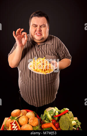 Fat man eating fast food french fries for overweight person. Stock Photo