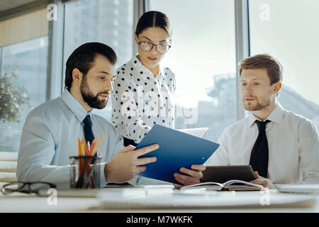 Pleasant secretary giving document copies to her boss Stock Photo