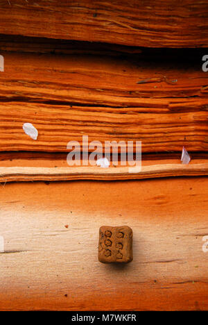 dice made from mud showing the number 6 lying on a split piece of cherry wood with some cherry blossom and wood grain depicting good luck win roll six Stock Photo
