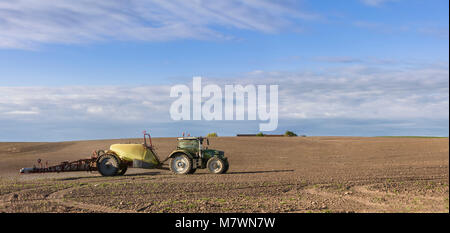 Tractor spraying fertilizer on agricultural field Stock Photo
