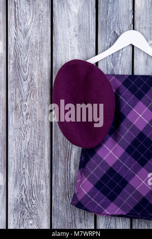 Set of women elegant apparel. Purple violet clothing. Dark wooden desk surface background. Stock Photo