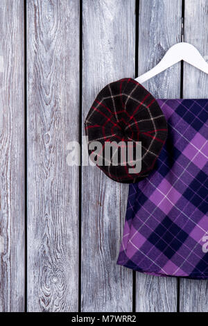 Flat lay of woman's autumn cozy clothes. Purple garment, top view. Dark wooden desk surface background. Stock Photo