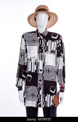 Stylish modern summer women's clothes outfit. Black and white shirt with abstract geometry print on mannequin. Straw summer hat and purse. Stock Photo