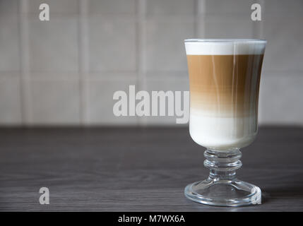 A frothy, Macchiato or cappucino coffee in a tall glass with a clean background Stock Photo