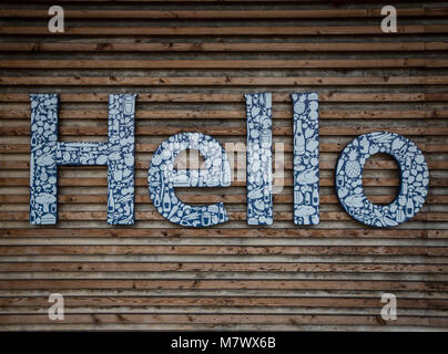 The word Hello written in large letters with consumer items printed in white  and on a wooden, slatted background welcoming customers and people. Stock Photo