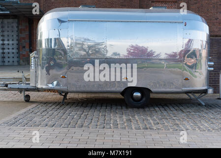 futuristic unmarked silver burger van with reflection of trees and space for caption Stock Photo