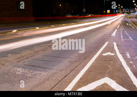 slow exposure from the middle of the road at night with vehicle lights passing by Stock Photo