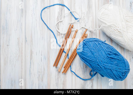 white and blue knitting threads and hooks for knitting on white old wooden table, selective focus. copy space, top view Stock Photo