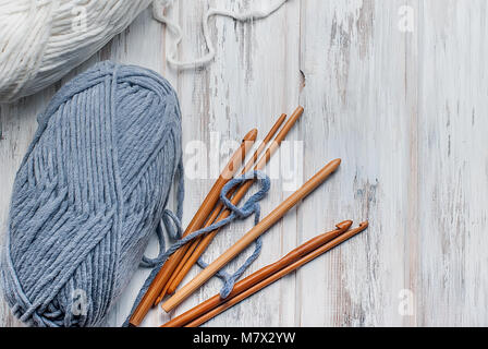 white and grey knitting threads and hooks for knitting on white old wooden table, selective focus. copy space, top view Stock Photo