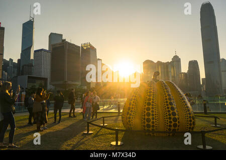 Harbour Arts Sculpture Park and art lovers taking photos of big pumpkin sculpture, Hong Kong skyline in background Stock Photo