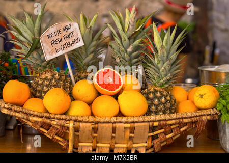 Wicker basket with oranges and pineapples on sale Stock Photo