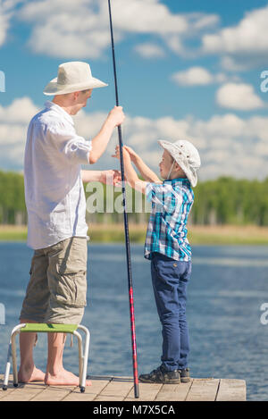 Father and little son fishing in the lake. Dad teaches son to fish