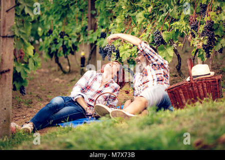 Beautiful cheerful couple having fun on picnic at a vineyard. Stock Photo