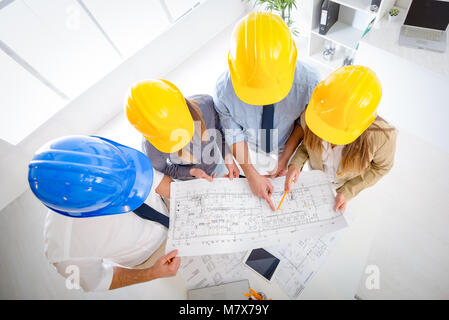 Young architect team discussing construction plans and planning what to change to be better. They are in the office. Top view. Stock Photo