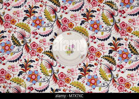 a flower plate hidden on a flowery fabric. Camouflage game. Minimal color still life photography. Stock Photo