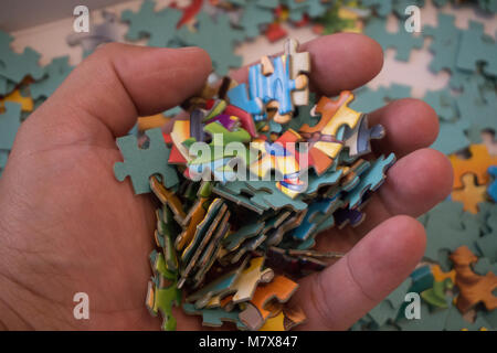 Close up of hand placing the puzzle , Hand holding missing jigsaw puzzle piece Stock Photo