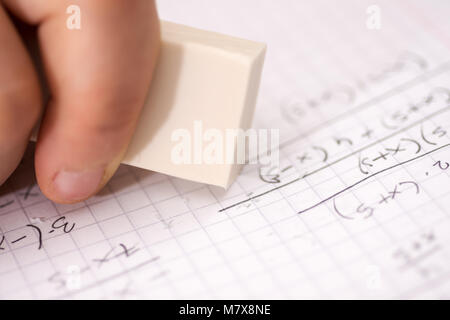 Hand with White Ruber Eraser on White Paper. Mistake Erase Concept. Stock Photo