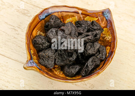 Dried plums heap in the bowl over wooden background Stock Photo
