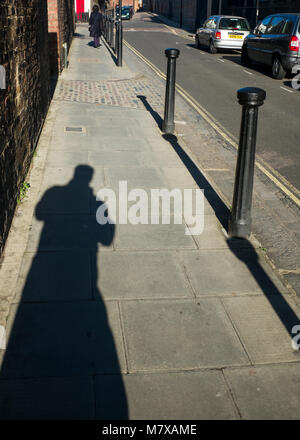 shadow of figure on street in bright sunlight Stock Photo