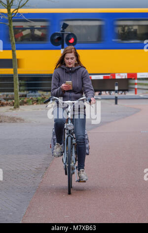 Young woman getting distracted by his smartphone while riding his bicycle around the city Stock Photo