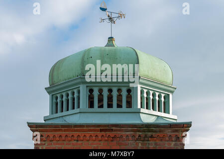 Copper green dome in Bexhill-on-Sea on a brick base, with a weathervane on top, photographed in the early spring sunshine. Mughal Architecture. Stock Photo