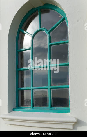 An arched window in the King George V Colonnade with a green frame and wide plastered surround; sunshine on two of the panes, Bexhill-on-Sea Stock Photo