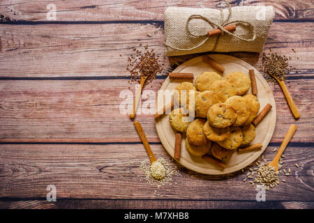 Freshly baked scones on a wooden plate with cinnamon sticks and different  spices on wooden spoons, top view Stock Photo
