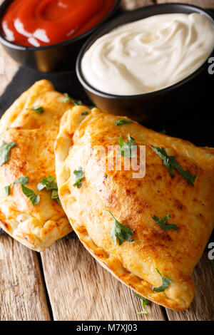 Italian closed pizza calzone with two sauces close-up on the table. vertical Stock Photo