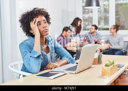 Young business start-up woman on laptop is thinking about difficult decision Stock Photo