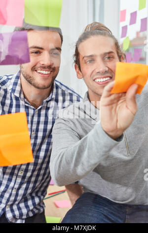 Young students in start-up team are writing down ideas on note in Ideas Workshop Stock Photo
