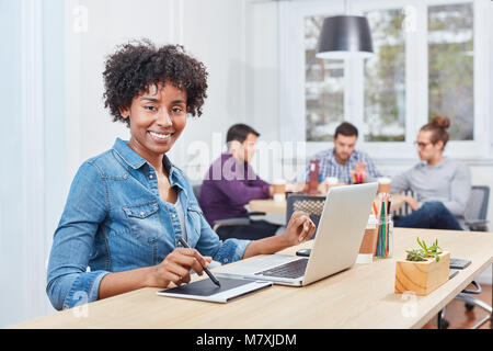 Creative young multicultural woman works as a graphic artist with graphics tablet and pen Stock Photo