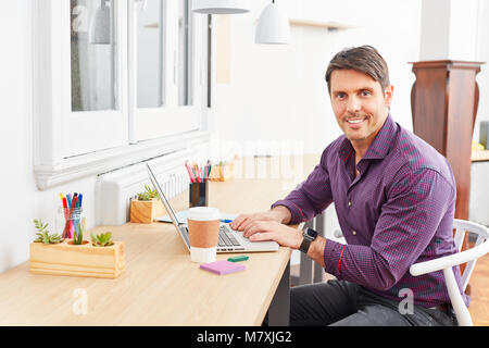 Young man as a self-confident start-up founder on laptop computer in the office Stock Photo