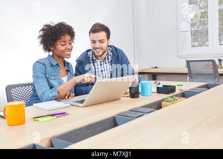 Two young programmers as a team developing on laptop computer Stock Photo