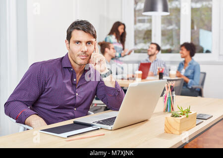 Young business man as thoughtful founder at laptop in coworking office Stock Photo