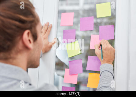 Businessman in a creative brainstorming exercise writes ideas on piece of paper Stock Photo